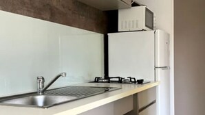 A compact kitchen with a stainless steel sink, a gas stove, and a white refrigerator.
