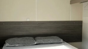A bed with a dark headboard, two pillows, and a white mattress cover.