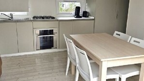 A compact kitchen with a gas stove, oven, and a window above the counter. - Mobile home for 6 with terrace in Charlieu (Charlieu)