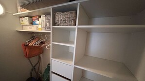 A closet with open shelves, a hanging rack, and a vacuum cleaner. - Apartment at slopes, Wifi included, sauna, 5 sleeps (Risoul)