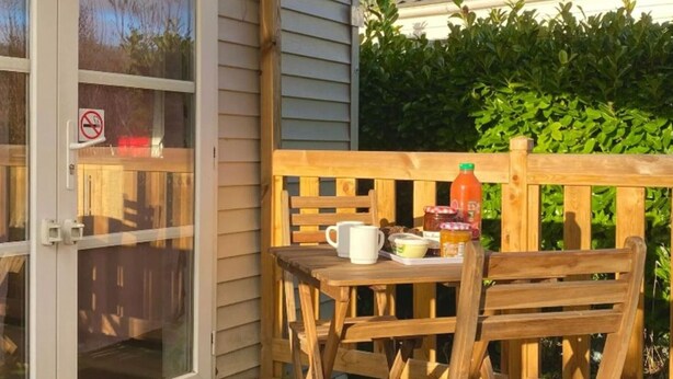 Eine Holzterrasse mit Tisch und Stühlen, einer Glastür und einem Rauchverbot-Schild.