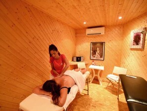 A wooden room with a massage table, a massage chair, a small table with bottles, and a framed picture on the wall. - Spacious mobile home with terrace, ideal for 8 people (Vias)