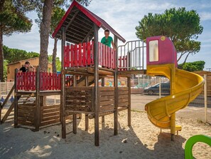 Une aire de jeux dotée d’une structure en bois, comprenant un toboggan et des zones d’escalade.