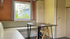 A room with a sofa, a table, and a window with curtains. - Family Mobile Home for 5 in Angicourt (Angicourt)