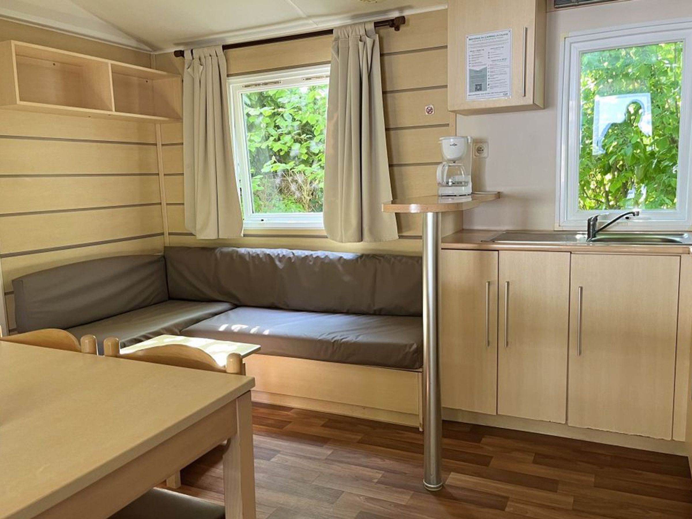 Een compacte kitchenette met een ingebouwde kookplaat, een gootsteen en een raam met gordijnen.