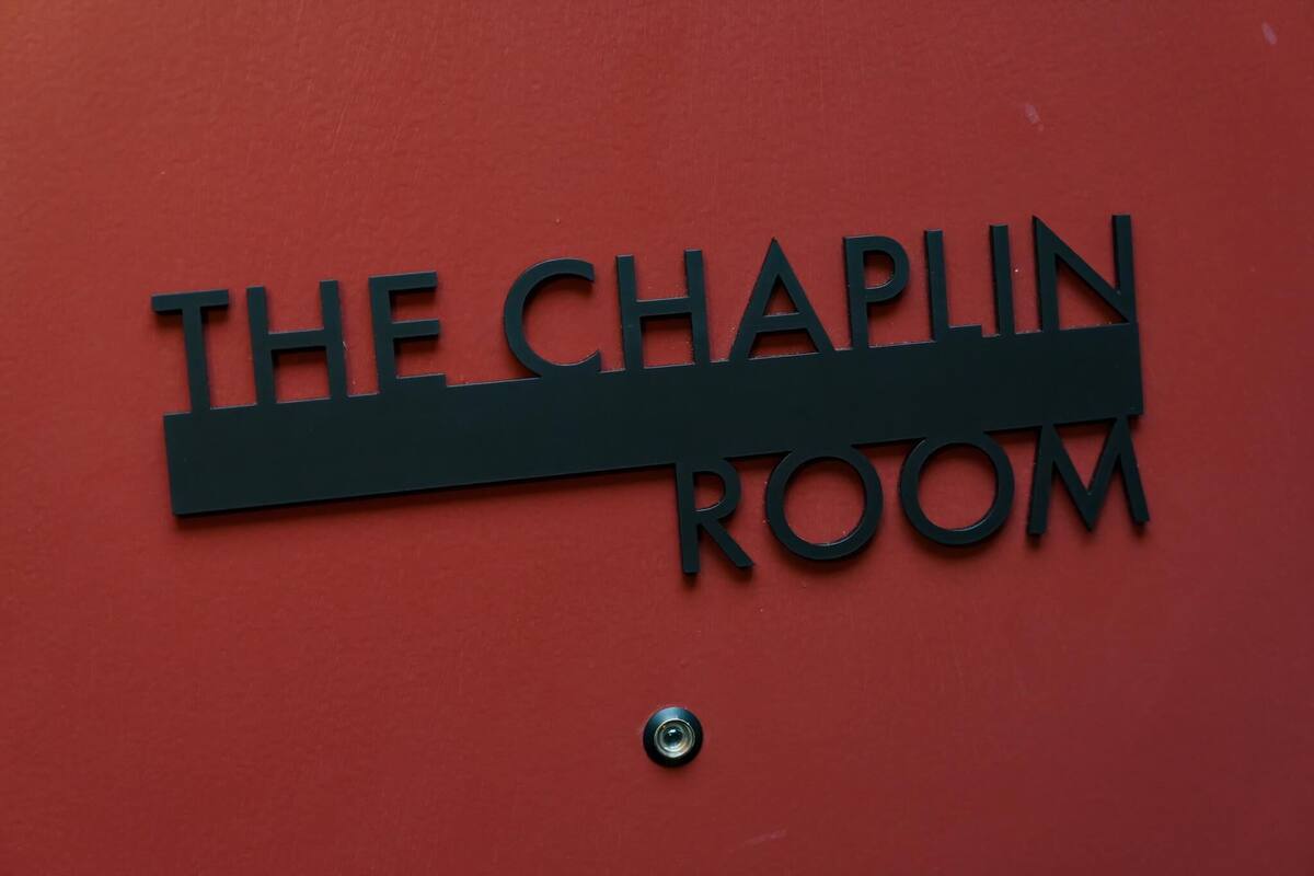 Ein Schild mit der Aufschrift 'The Chaplin Room' an einer roten Wand.
