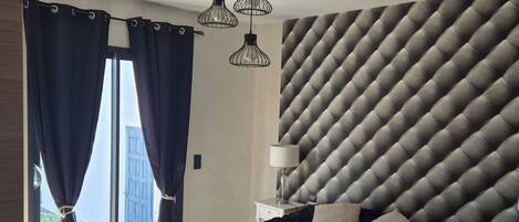 A bedroom with a bed, a nightstand, a lamp, and a wall with a geometric pattern.