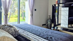 Ein Schlafzimmer mit einem großen Bett, einem Fernseher und Blick ins Freie.