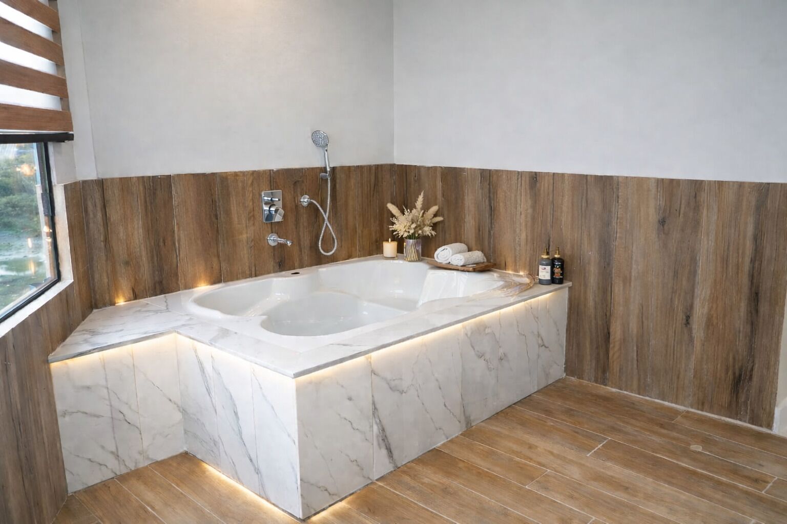 A modern bathroom with a freestanding bathtub, wooden paneling, and a window providing natural light.