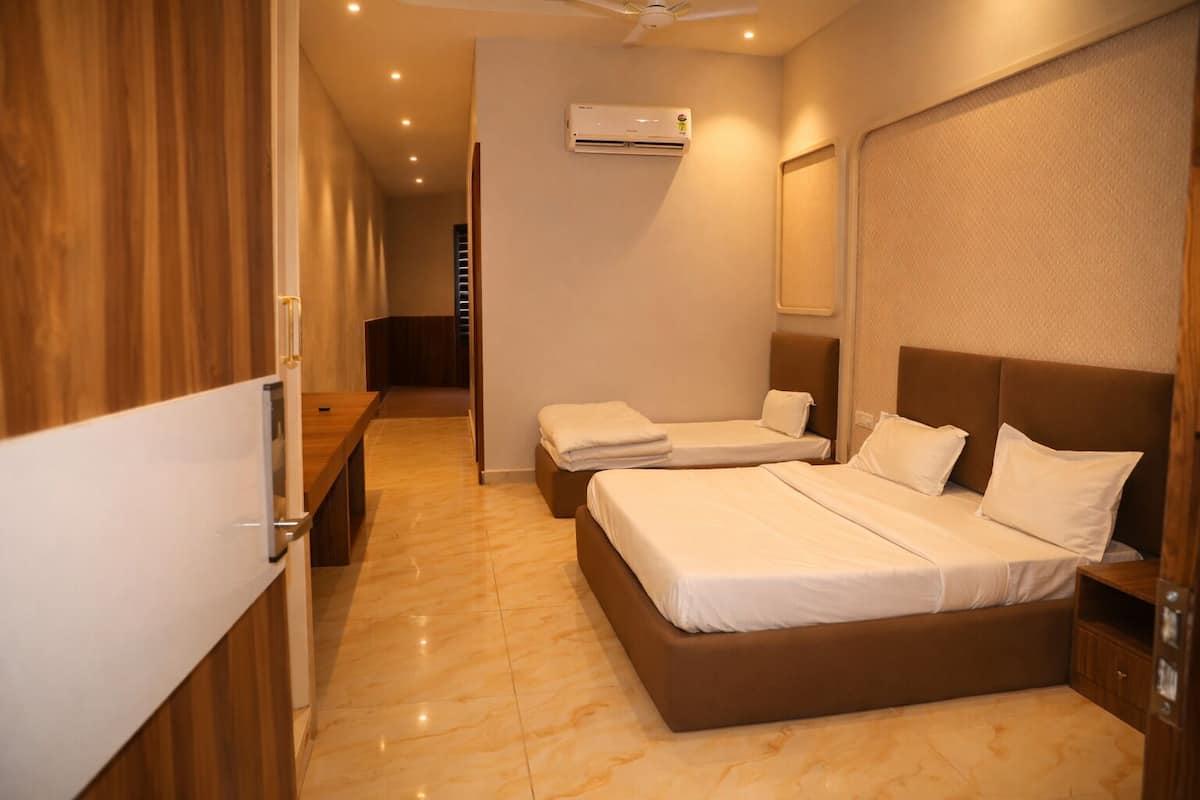 Une chambre d’hôtel avec deux lits, un ventilateur de plafond, un appareil de climatisation et une armoire en bois.