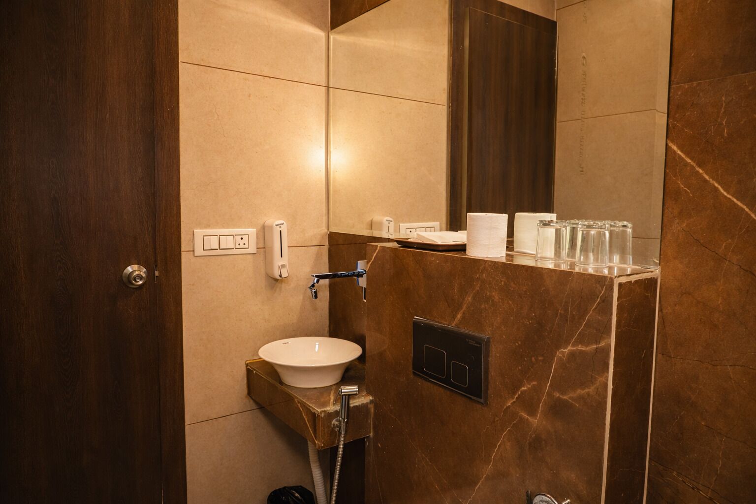 Un baño moderno con lavamanos de mármol, un espejo y dispensador de papel higiénico.