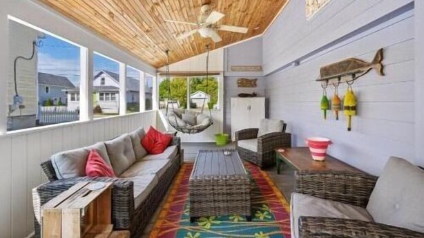 A covered porch with wicker furniture, a ceiling fan, and a view of houses outside. - Coquina Cottage - close to town - wifi - Linens and Towels are provided (Chincoteague)