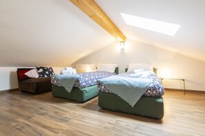 Ein Schlafzimmer mit zwei Betten, einer Schlafcouch und einem Dachfenster.