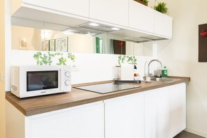 Eine moderne Küche mit weißen Schränken, einer Mikrowelle, einem Spülbecken und einer Arbeitsplatte.