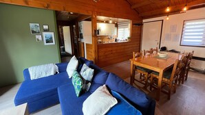 Ein gemütliches Wohnzimmer mit einem blauen Sofa, einem Holzespeisebereich und einer Küche im Hintergrund.