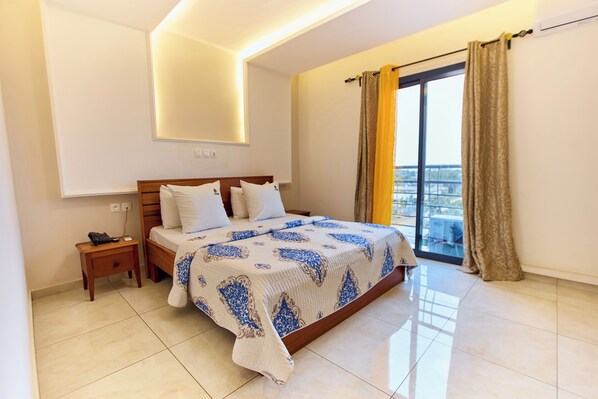 A bedroom with a bed, bedside table, and a window with curtains. - Helena Home - Kribi (Kribi)
