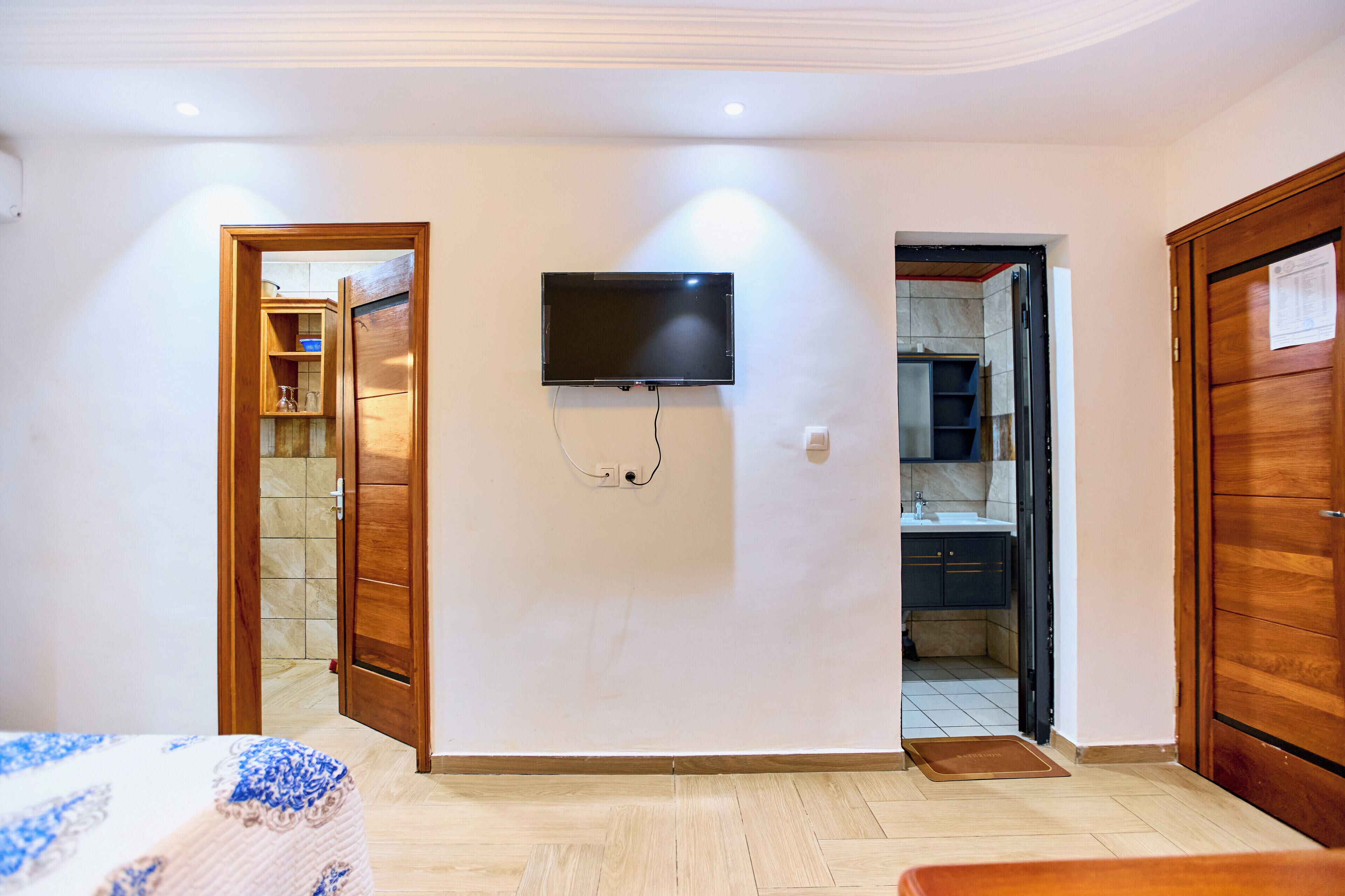Een kamer met een bed, een aan de muur bevestigde televisie en een deur naar een badkamer.