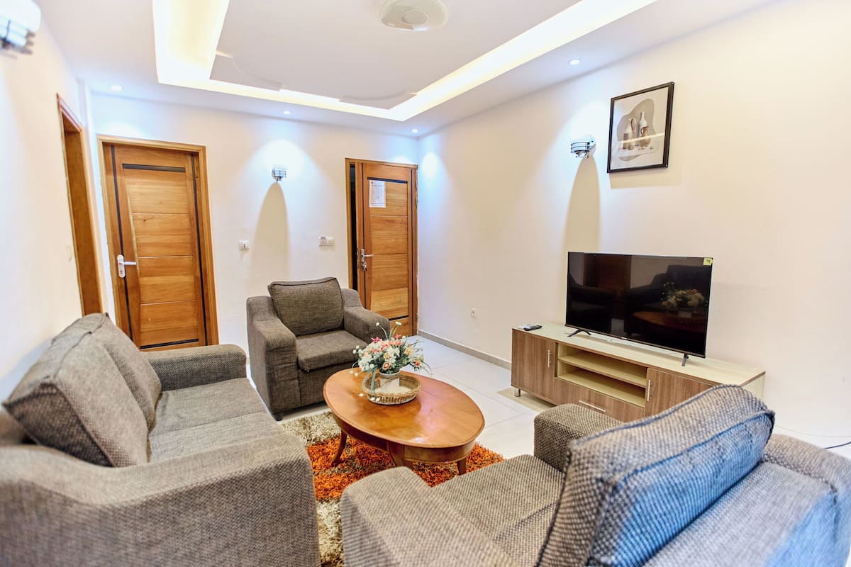 A modern living room with two sofas, a coffee table, a TV, and wooden doors.