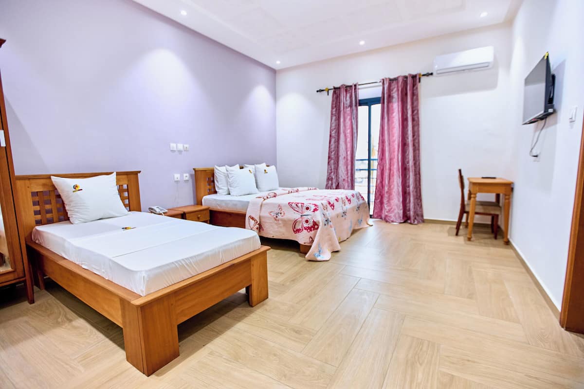 A hotel room with two wooden beds, a small desk, and a TV mounted on the wall.