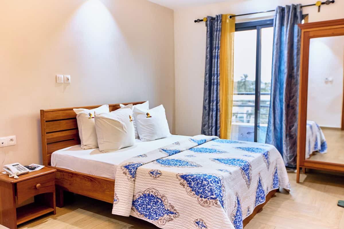 A bedroom with a wooden bed, white bedding, and a patterned bedspread.