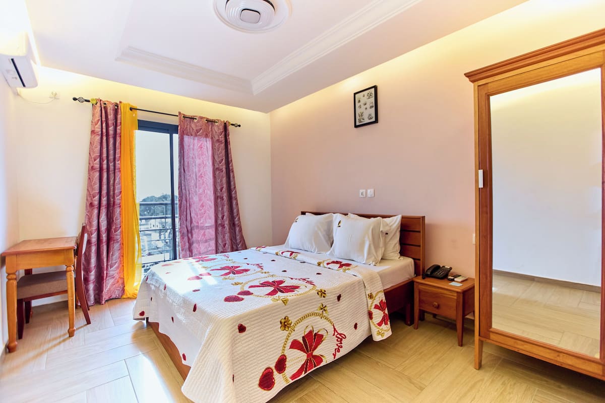 A bedroom with a bed, bedside table, and a large mirror.