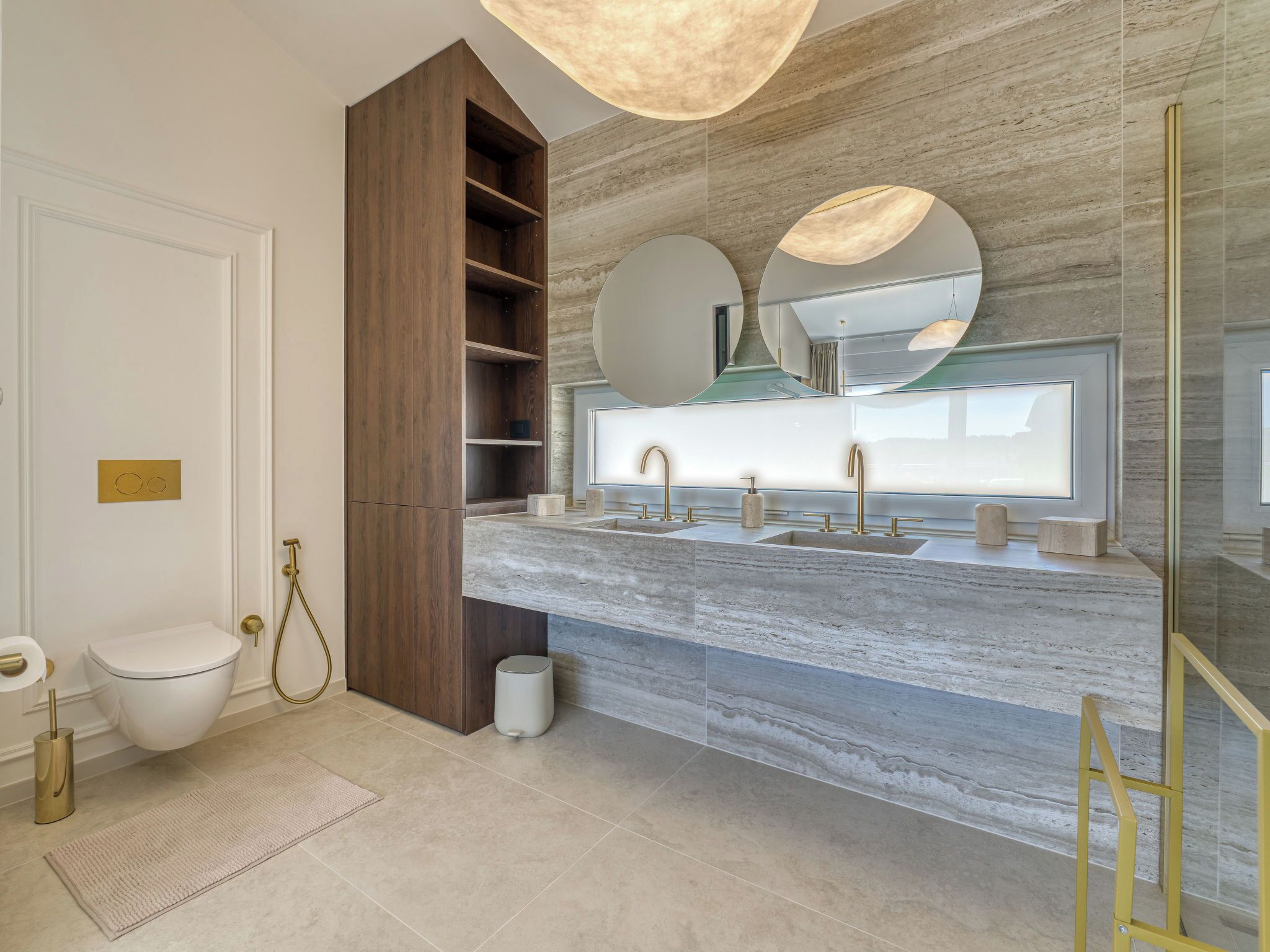 A modern bathroom with a marble countertop, dual sinks, a wooden vanity, a toilet, and a large mirror.