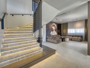 A modern interior with a staircase, a sectional sofa, and a wall-mounted artwork.