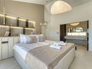 A modern hotel room with a large bed, a vanity with a mirror, and a view of the outdoors.
