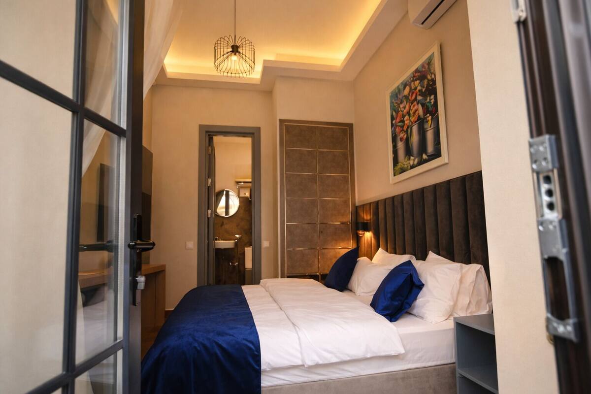 Una habitación de hotel moderna con una cama grande, un vestidor, un baño y un comedor.