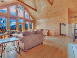 Eine geräumige Holzhütte mit großem Sofa, Esstisch und Küchenbereich.