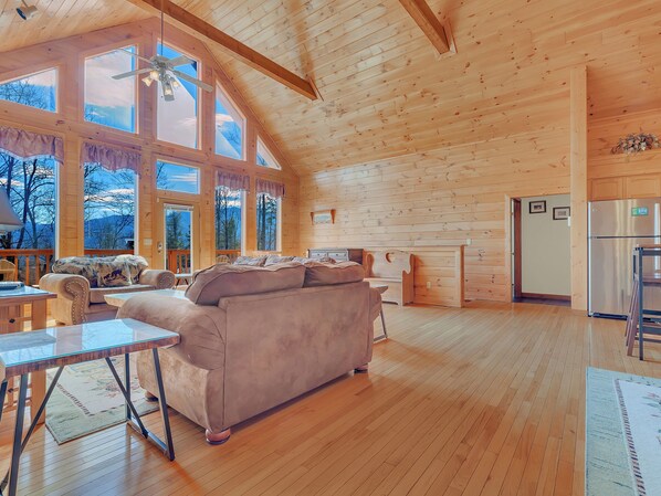 Une cabane en bois spacieuse, dotée d’un grand canapé, d’une table à manger et d’un coin cuisine.