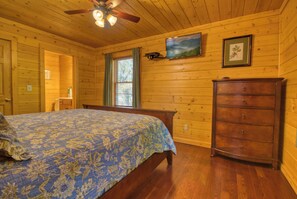 A wooden-paneled bedroom with a bed, dresser, and a ceiling fan. - Downtown Cabin|Private Pool|Hot Tub|Game Room (PIGEON FORGE)