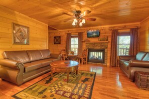 A cozy cabin interior with a wooden ceiling, leather sofas, a fireplace, and a television mounted above it. - Downtown Cabin|Private Pool|Hot Tub|Game Room (PIGEON FORGE)