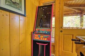 A vintage arcade machine in a wooden room with a door and window. - Downtown Cabin|Private Pool|Hot Tub|Game Room (PIGEON FORGE)