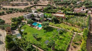 An aerial view of a property with a swimming pool, green lawns, and surrounding vegetation. - Dar Fatima Tamazouzt (Tamazouzte)