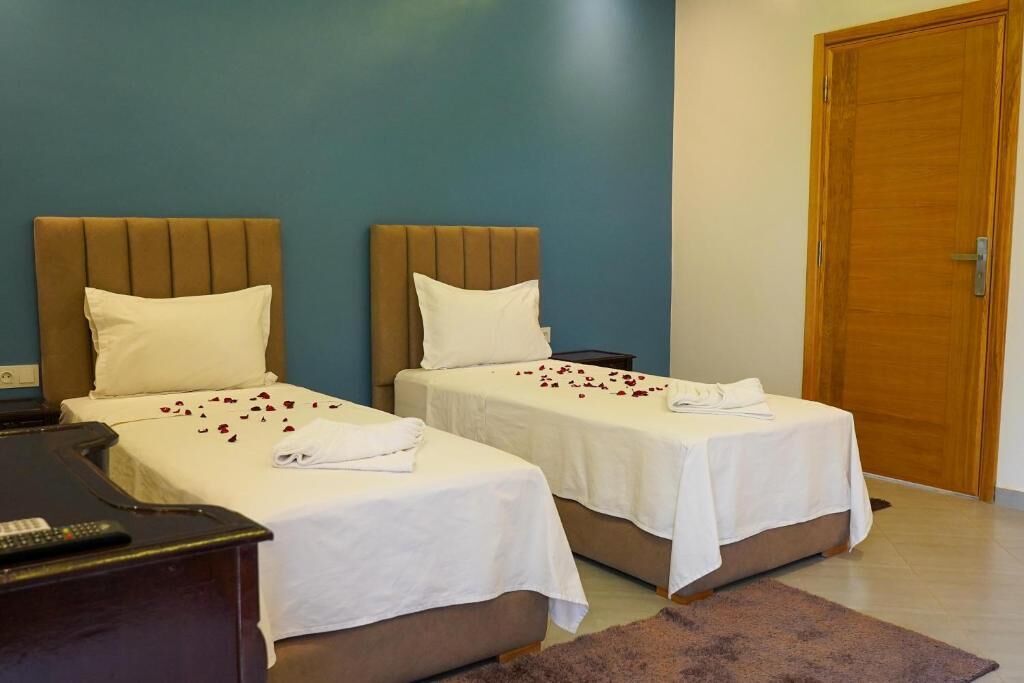 A hotel room with two beds, a desk, and a wooden door.