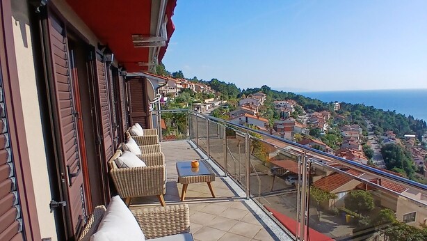 Un balcone con mobili in vimini e vista su una località costiera.