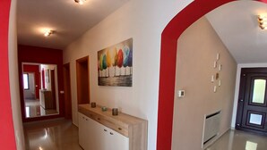 Un corridoio con un tavolo consolle in legno, un quadro e una parete colorata di rosso.