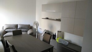 A modern living room with a sofa, a dining table, and a built-in shelf. - Beautiful Apartment 1br/4p - At the Gates of Milan (Sesto San Giovanni)
