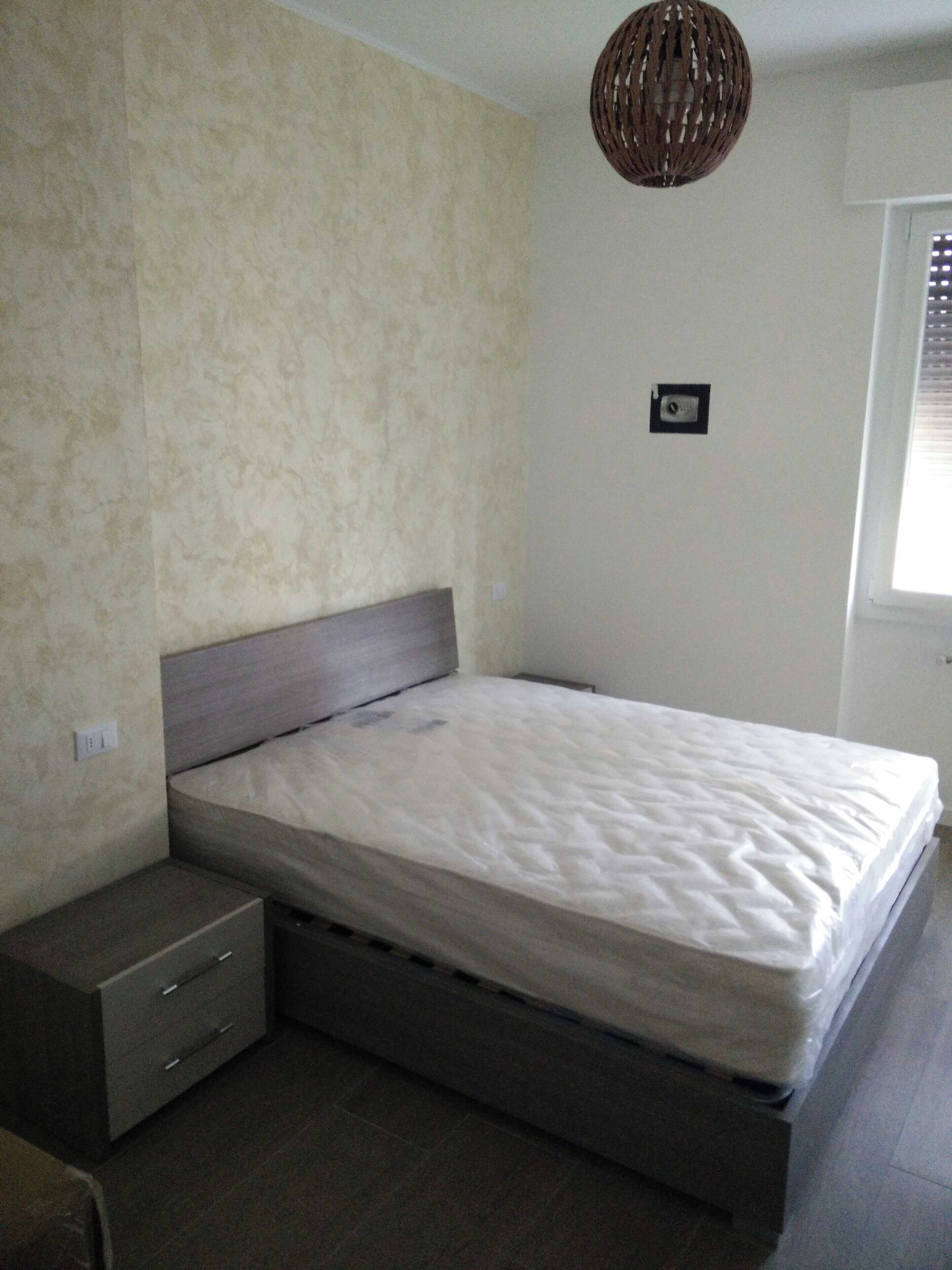 Une chambre à coucher comprenant un lit, une table de chevet et un luminaire fixé au mur.
