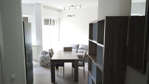 A modern living room with a dining table, sofa, and built-in shelving. - Beautiful Apartment 1br/4p - At the Gates of Milan (Sesto San Giovanni)