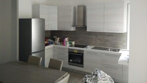 A modern kitchen with white cabinets, a built-in oven, and a refrigerator. - Beautiful Apartment 1br/4p - At the Gates of Milan (Sesto San Giovanni)