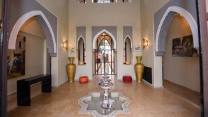 A spacious lobby with high ceilings, arched doorways, and a central fountain.