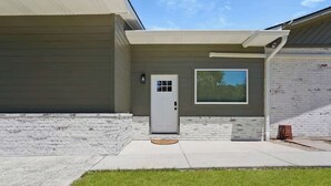 A modern house with a grey exterior, a white door, and a window with blinds.