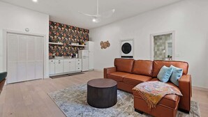 A modern living room with a brown leather sofa, a round coffee table, and a patterned rug.