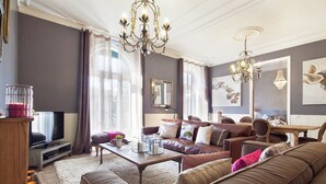 Un salon spacieux avec un grand canapé en cuir marron, une table basse en bois et un téléviseur posé sur un meuble.