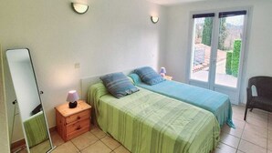 Ein Schlafzimmer mit zwei Betten, einem Spiegel, einem Nachttisch und einem Sessel.