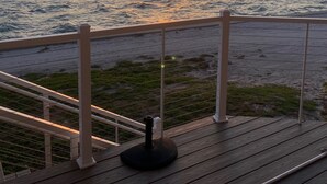 Terassi, jossa on kaide, jolta avautuu näkymä vesistöön ja kaupungin siluettiin horisontissa auringonlaskun aikaan.