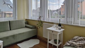 Une pièce avec un canapé vert, un radiateur blanc et une table sur laquelle se trouvent une bouteille et un verre.