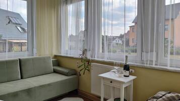 Ein Zimmer mit einem grünen Sofa, einem weißen Heizkörper und einem Tisch mit Flasche und Glas.
